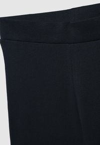 Czarne legginsy z elastycznym pasem, wykonane z gładkiego, cienkiego materiału. Posiadają czyste szwy i dopasowany krój.