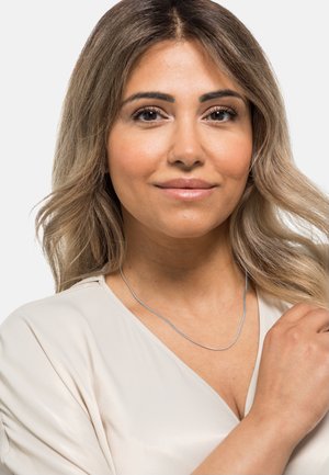 Silberne Kettenhalskette, die über einer hellen Bluse getragen wird, mit einer zarten, glatten Textur und einem einfachen, eleganten Design.