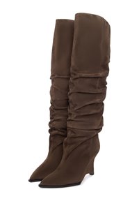 Barna szövet térd fölé érő csizma laza szabással, hegyes orral és ék sarkakkal. Sima textúra, a szár mentén ráncolt részletekkel.