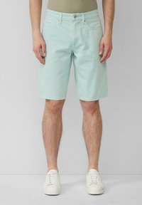 Shorts en denim vert menthe clair avec un design classique à cinq poches, coupe droite et accents cousus. Associés à des baskets blanches.