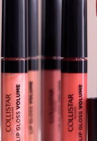 Collistar läppglans i volymförpackningar i olika nyanser av rosa och nude, med svarta lock och genomskinliga kroppar som visar den glansiga texturen och skimret.