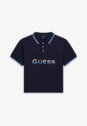 Polo bleu marine à manches courtes, avec une patte de boutonnage à trois boutons, un col et des poignets rayés bleu et blanc, et le logo "GUESS" en dégradé bleu sur la poitrine.
