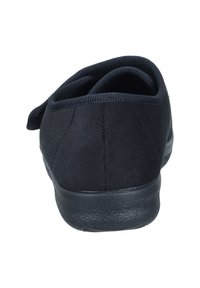 Black shoe with a soft suede texture, rounded back, padded collar, and a rubber sole. Features minimalistic design and no visible hardware.