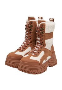 Botas de tobillo de piel sintética marrón forradas de piel con suela gruesa, que presentan una mezcla de paneles lisos y texturizados, y detalles de hardware en bronce.