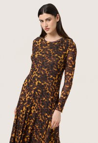 Langdurige mouwen, jurk met luipaardprint in tinten van bruin, oranje en zwart. Gemaakt van een doorschijnende, lichtgewicht stof met een ronde hals.