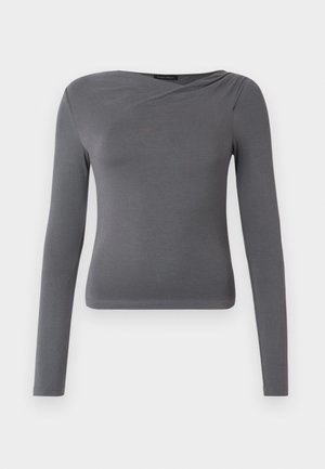 Grå topp med lange ermer i et mykt, elastisk stoff. Har en stilig kryssende utringning og en tettsittende passform med rett nederkant.