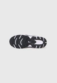 Černobílá sportovní podrážka obuvi s texturovanými gripovými vzory. Obsahuje výrazné logo Nike, vyrobené z gumového materiálu.