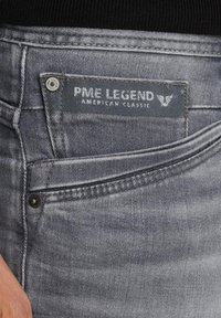 Sive traperice s izblijedjelim završnim slojem, teksturiranom površinom i markiranom oznakom "PME LEGEND AMERICAN CLASSIC."
