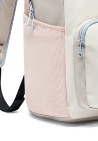 Hátizsák, amelynek világosbarna felső része, puha rózsaszín alsó szakasza, szürke cipzárai és sima felületű, texturált anyaga van.