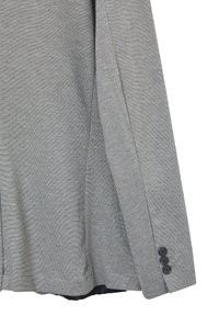 Graues Langarmshirt aus strukturiertem Stoff, mit tailliertem Schnitt und drei schwarzen Knöpfen an den Manschetten zur Befestigung.