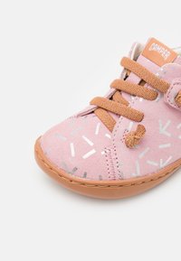 Rosa Wildleder-Schuh mit metallischen Akzentmustern, brauner Gummisohle und braunen Schnürsenkeln. Verfügt über ein gebrandetes Etikett auf der Zunge.