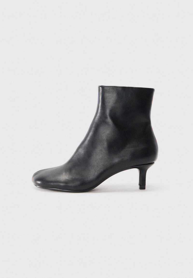 Stivale in pelle nera alla caviglia con punta affusolata e tacco sottile. Texture liscia e design senza cuciture, caratterizzato da un gambale alto e uno stile minimalista.
