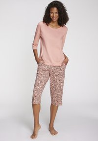 Light pink long-sleeve top paired with knee-length pants featuring a leopard print in shades of pink and black. Smooth fabric texture throughout.