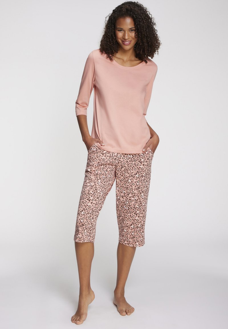 Light pink long-sleeve top paired with knee-length pants featuring a leopard print in shades of pink and black. Smooth fabric texture throughout.