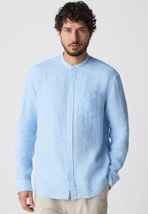 Light blue long-sleeve shirt with a mandarin collar, textured fabric, front pocket, and button closure, featuring a straight hemline.