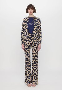 Navy and beige patterned blazer and wide-leg trousers set, made from smooth fabric, featuring abstract geometric designs.