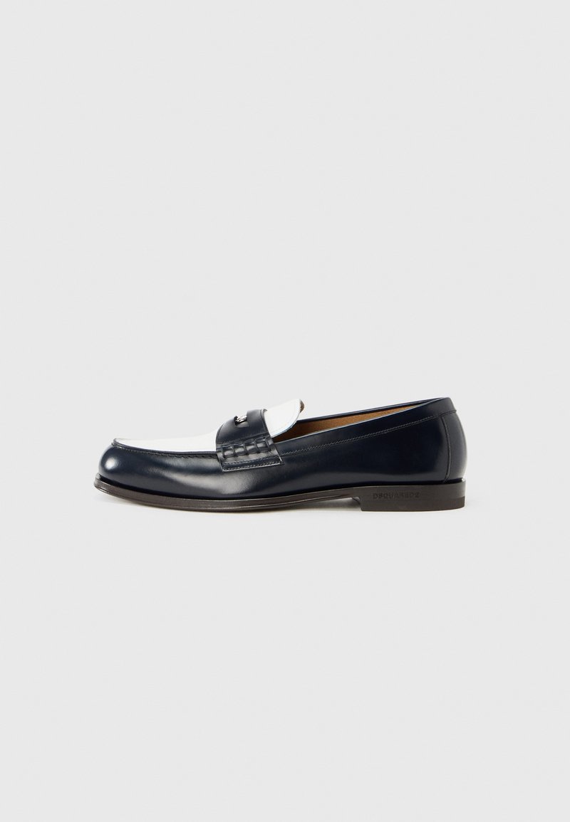 Marineblauwe leren loafer met een witte en getextureerde band, een glad bovenwerk en een lage hak, met een decoratief metalen accent aan de voorkant.