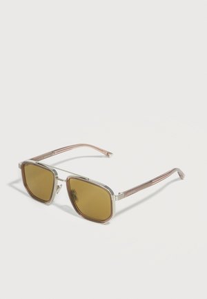 Quadratische Sonnenbrille mit braun getönten Gläsern, silbernen Metallrahmen und durchsichtigen, hellrosa Bügeln mit der Marke "Gucci".