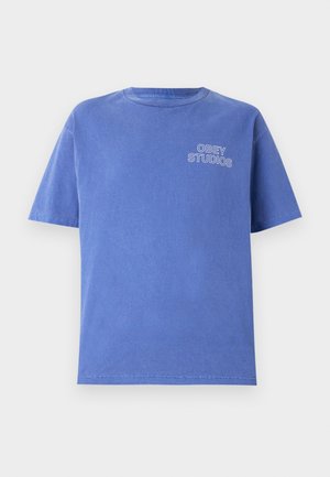 Blue cotton t-shirt with short sleeves, crew neck, and "OBEY STUDIOS" printed in white on the left chest. Simple design, unisex fit.
