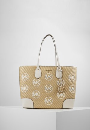 Beżowa pleciona torba na ramię z białymi skórzanymi wykończeniami, podwójnymi rączkami i wieloma białymi okrągłymi logo "MK" na froncie, wyeksponowana na białym postumencie.