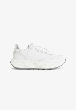 Baskets de sport blanches avec une tige en cuir lisse, un accent de talon gris texturé, des lacets bien visibles et une semelle à motif en vagues.