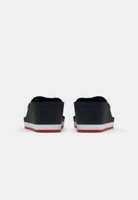 Black platform sandals with wedge design, featuring a white and red layered sole. Textured straps and rounded toe area.