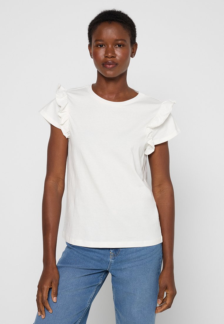 Weißes kurzärmliges T-Shirt mit Rüschendetails an den Schultern, aus weichem Baumwollstoff. Kombiniert mit blauen Jeans.