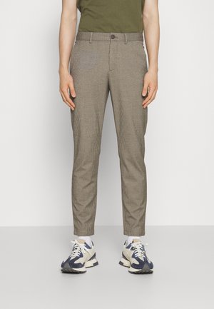 Brune ternede bukser med en slim fit, der har en knaplukning, sidelommer og en glat tekstur, parret med hvide og marineblå sneakers.
