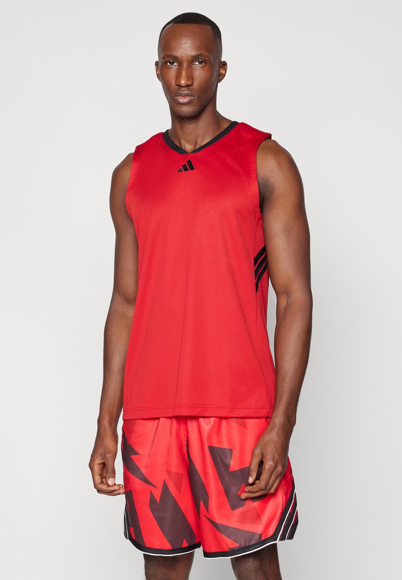 Röd atletisk tanktopp med svarta accents, i kombination med röda shorts som har ett svart abstrakt geometriskt mönster, tillverkade av lätt material.
