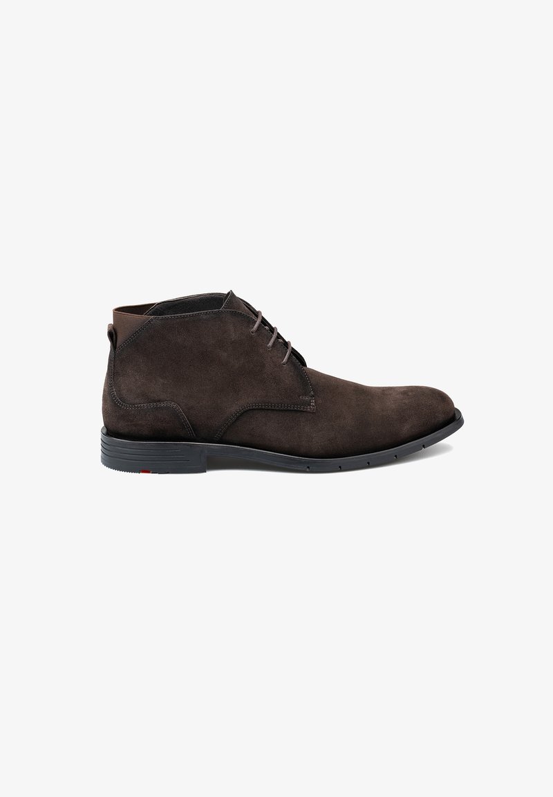 Stivaletti alla caviglia in suede marrone con punta tonda, chiusura con lacci frontale e suola in gomma nera con accenti rossi. Texture liscia su tutta la superficie.