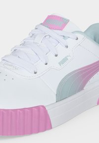 Λευκό αθλητικό παπούτσι Puma με ροζ και γκρι διαβαθμισμένη ρίγα, λευκά κορδόνια, ροζ καουτσούκ σόλα μπροστά και ροζ λογότυπο Puma στη γλώσσα.
