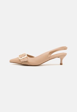 Beżowe czółenka typu slingback na obcasie kitten z szerokim paskiem i złotą klamrą na jednolitym tle.