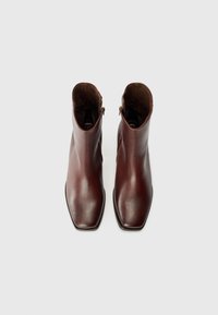 Brown leather ankle boots with a smooth finish and square toe design. Side zipper closure and minimal stitching details.