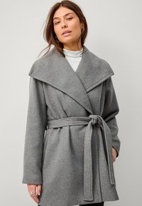 Grijze wolmix jas met een brede kraag, een ceintuurbundeling in de taille en lange mouwen. Zachte textuur met een gestructureerd maar ontspannen silhouet.