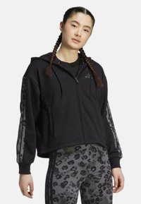 Felpa nera cropped in tessuto morbido, con chiusura a zip, tasche frontali e dettagli a contrasto con stampa leopardata sulle maniche.