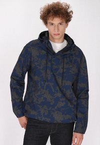Jachetă pulover de culoare bleumarin cu un model hexagonal, având glugă, șnururi ajustabile și croială lejeră.