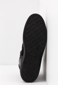 Musta kengänpohja, jossa on teksturoitu kumipinta ja geometrisia kuvioita. Brändin nimi "PETER KAISER" on kohopainettuna pinnassa.