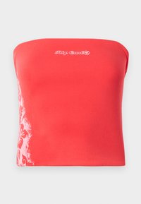 Piros, pánt nélküli crop top, fehér virágmintával a bal oldalon és a középen hímzett "Rip Curl" logóval.