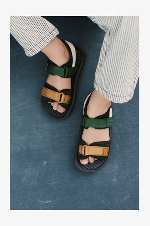 Svart- og grønnsandaler med justerbare stropper i brunt og grønt. Gummisåle, polstret innleggssåle og tåstroppdesign.