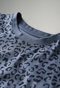 T-shirt con stampa leopardata in grigio scuro con macchie nere. Presenta un collo a girocollo a coste e una texture di tessuto liscia.