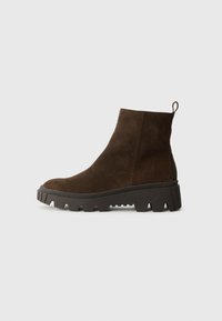 Brun ruskindsankelstøvle med en kraftig sort gummisål, der har en let hæl og en slip-in hækling for nem påklædning.