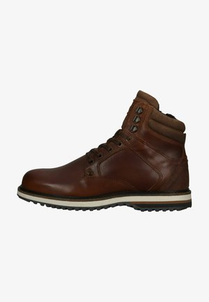Bottines en cuir marron avec des accents en daim, bout arrondi, laçage à six œillets et semelle en caoutchouc texturé avec des rayures blanches et noires.