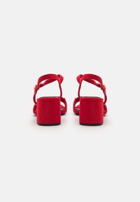 Røde semskede blokkheel sandaler med dobbelt stroppedesign og ankelspenne, med en jevn tekstur og solid konstruksjon.