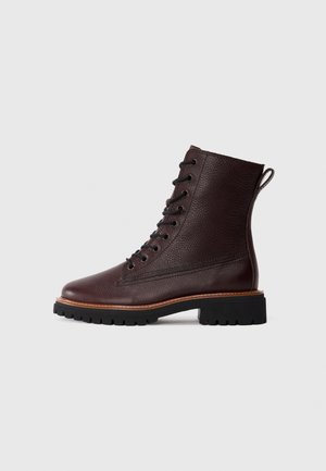 Stivale alla caviglia in pelle textured marrone scuro, con lacci, suola in gomma nera e cucitura in tan, mostrato di profilo su sfondo bianco.