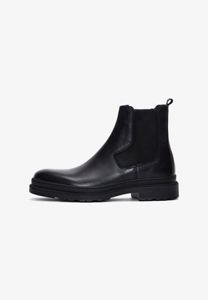 Bottine Chelsea en cuir noir avec panneau élastique sur le côté, languette à l'arrière et semelle en caoutchouc épaisse, présentée de profil sur fond blanc.