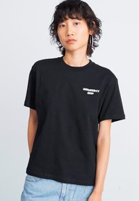 Black cotton t-shirt featuring a round neckline and short sleeves, with a small white logo detail on the upper left side.
