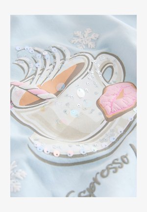 Svetlo modra tkanina z ilustracijo skodelice kave z bleščicami, rožnatim odtisom ustnic in poudarki snežink. Vzorci so natisnjeni s subtilnimi teksturami.