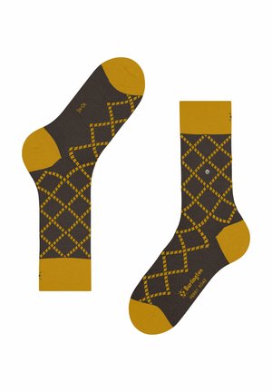 Braune Socken mit senfgelbem Fersen-, Zehen- und Bündchenbereich, die ein Rautenmuster aufweisen und an einer Seite einen kleinen Metallknopf haben.