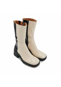 Bottes en cuir montantes avec des panneaux crème et noir, dotées d'une fermeture éclair sur le côté, d'un bout carré et d'un talon en caoutchouc épais. Texture lisse.