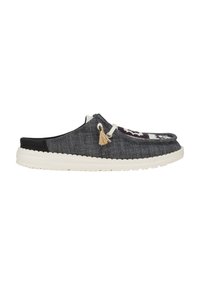 Zapato tipo slip-on de tela gris con parte trasera negra y suela de goma blanca. Presenta borlas decorativas y un diseño frontal con patrones.